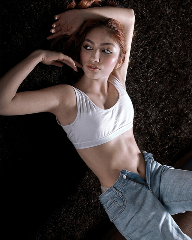 Black and white photograph of a man looking at the camera behind some fabrics that are in the air.