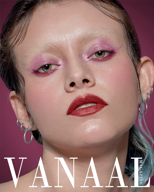 Black and white photograph of an entity covered by a robe, seated on a chair, in front of which hands hold an open book from which butterflies are emerging.