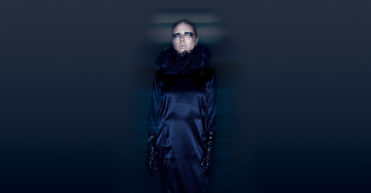 Fotografía editorial Androgena de modelo vestida con un vestido largo de color azul oscuro y guantes negros.