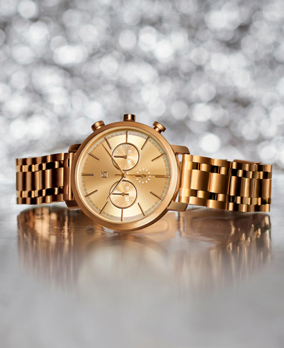 Fotografía de producto reloj dorado sobre superficie metálica.